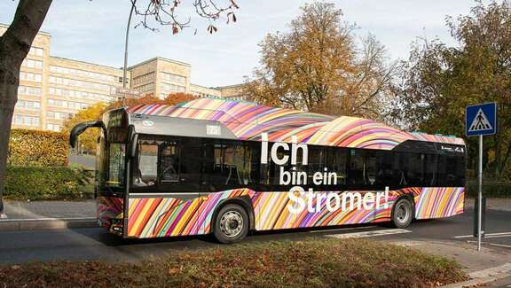 Vergrößerte Ansicht: Bunter Bus mit der Aufschrift "Ich bin ein Stromer"