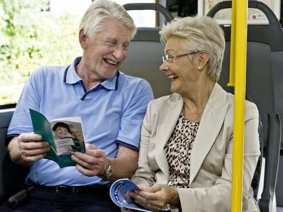 Älteres Paar sitzt lachend im Bus