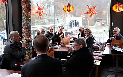 Beteiligte der Aufsichtsratssitzung versammeln sich in einem Restaurant und stoßen an.