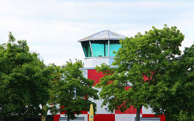 Rotweißer Tower verdeckt von grünen Laubbäumen