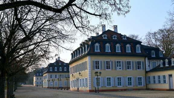 Quadratisches historisches gelbes Gebäude mit vielen Fenstern und einem schrägen Dachgeschoss