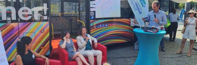 Drei Frauen sitzen auf dem roten Sofa vor dem Mobilitätsbus.