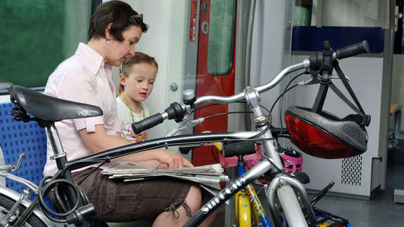 Woman and a young girl sitting in a train with their bikes