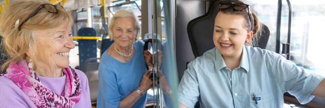 Seniorin kauft eine Fahrkarte im Bus.