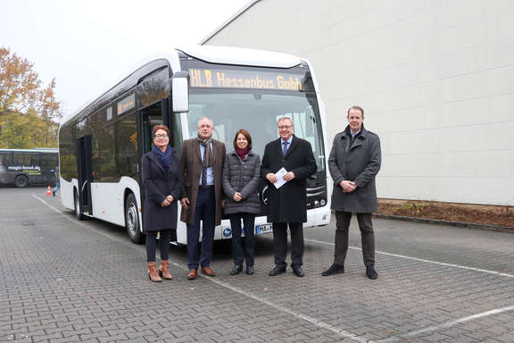 Die Beteiligten stehen vor einem Elektrobus der HLB Hessenbus GmbH. HLB Hessenbus erhält Fördermittel für E-Busse.