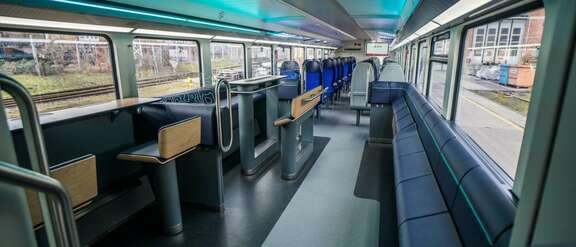 Innenraum eines Großraumwaggons mit Arbeitstheke, Tresen mit Sitzen und Stehhilfen