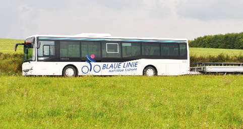 Blue line bus with bike trailer in the landscape