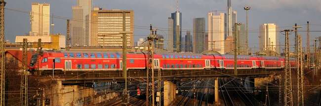 S-Bahn fährt über Brücke vor Frankfurter Skyline