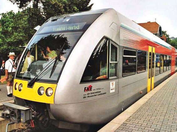 Vergrößerte Ansicht: Grauer Zug mit gelben und roten Elementen steht am Bahnhof