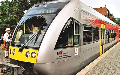 Vergrößerte Ansicht: Grauer Zug mit gelben und roten Elementen steht am Bahnhof