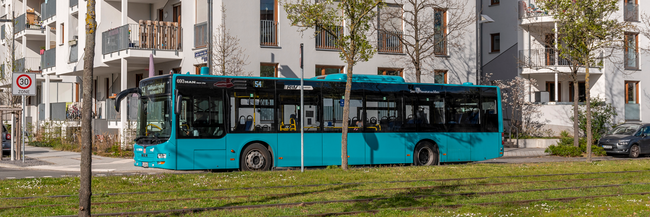 Ein türkisfarbener Bus vor einem Hochhaus