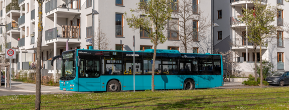 Ein türkisfarbener Bus vor einem Hochhaus