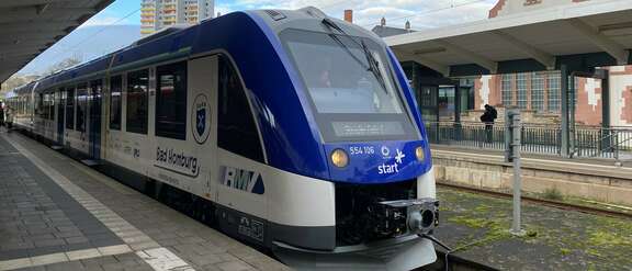 Blauweißer Zug steht auf einem Gleis im Bahnhof