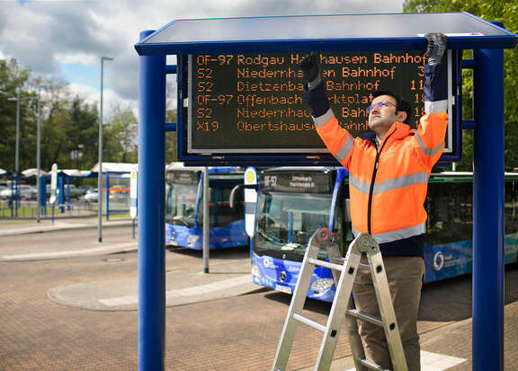 Ein Mitarbeiter der kvgOF wartet eine digitale Anzeige.