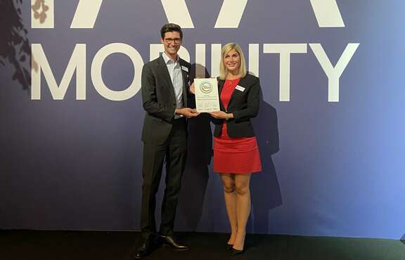 Mobility-Award: Ein Paar steht vor einer Wand mit dem Text IAA Mobility, hält eine Auszeichnung