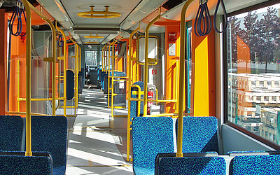 Vergrößerte Ansicht: Innenraum der U-Bahn mit blauen Sitzen und gelben Haltestangen