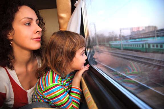 Young woman and a young girl are looking out of a train window