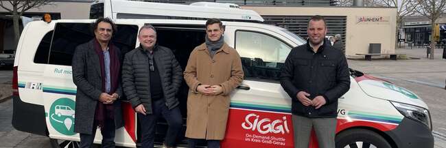 Vier Personen vor einem SiGGi-Kleinbus
