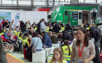 Viele Erwachsene mit Kindern in der Halle der S-Bahn-Werkstatt, im Hintergrund rote und grüne S-Bahnen