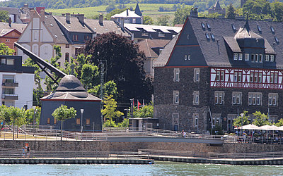 Vergrößerte Ansicht: Häuser am Rheinufer. Vorne links: alter Kran. Vorne rechts: Steinhaus oben mit Fachwerk