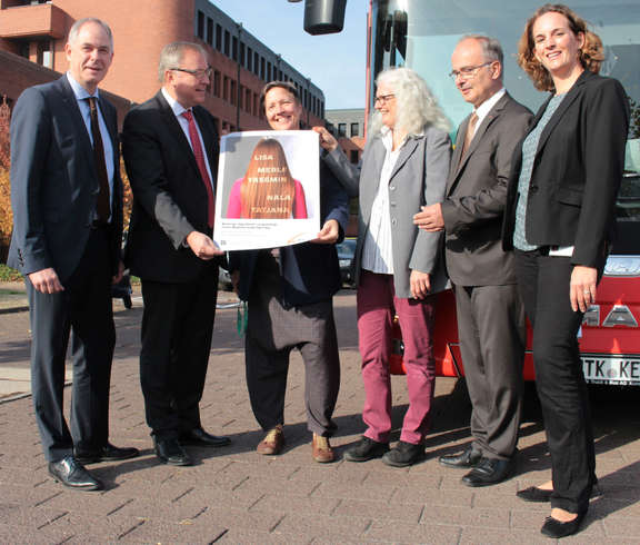 Teaserbild: Plakataktion Beteiligte stehen vor einem MTV-Bus und halten das Plakat der Kampagne hoch. Die MTV unterstützt Plakataktion gegen Gewalt an Mädchen.
