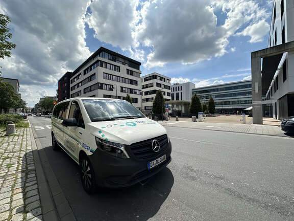 Ein größeres weißes Auto steht auf einer Straße vor einer Klinik