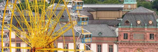 Ein großes gelbes Riesenrad vor dem Hintergrund historischer Gebäude in Darmstadt
