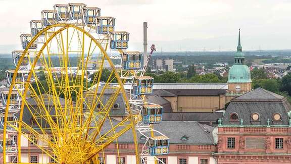 Ein großes gelbes Riesenrad vor dem Hintergrund historischer Gebäude in Darmstadt