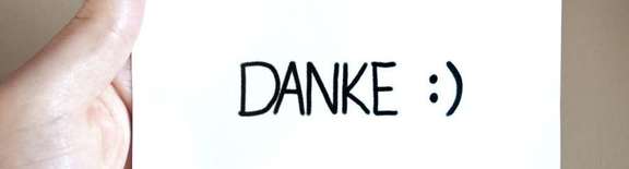 Hand hält Zettel mit dem Wort "DANKE" und einem Smiley