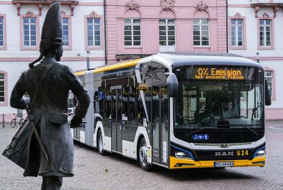 seitliche Aufnahme eines Busses, im Vordergrund ist der Mainzer Fastnachtsbrunnen