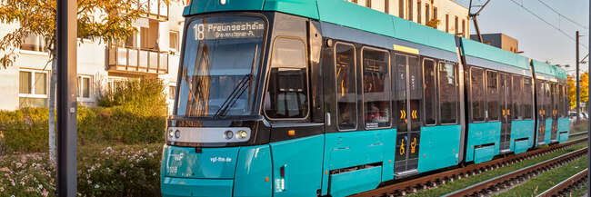 Eine mintgrüne Straßenbahn vor Wohnhäusern