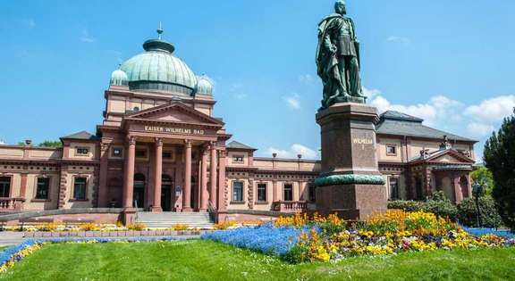 Vergrößerte Ansicht: Frontansicht Kaiser-Wilhelms-Bad mit Rundkuppel, Säuleneingang, große Statue Kaiser Wilhelm I