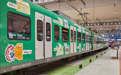 Grün lackierte S-Bahn mit Kinderbildern