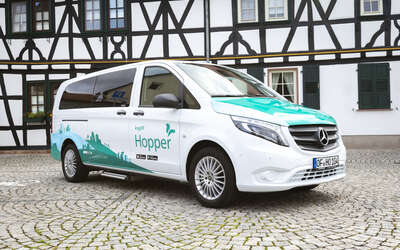 Ein Kleinbus steht vor einem Fachwerkhaus. Aufschrift: eHopper