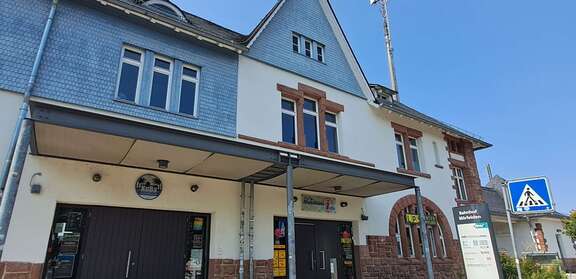 Ein altes Gebäude mit einem Aufsteller davor, Schrift: Bahnhof Mörfelden