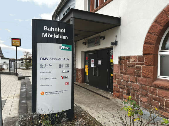 Ein altes Gebäude mit einem Aufsteller davor, Schrift: Bahnhof Mörfelden