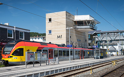 Bahnsteig und Gleise, rechts: Zug der mit Aufschrift HLB
