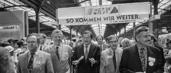 Schwarz-weiß-Foto im Frankfurter Hauptbahnhof mit Hans Eichel, Ministerpräsident des Landes Hessen (1991-1999), Lothar Klemm, Hessischer Verkehrsminister (1994-1999), Achim Exner, Oberbürgermeister der Stadt Wiesbaden (1985-1997), Jochen Riebel, Landrat des Main-Taunus-Kreises (1990-1999) und Volker Sparmann, RMV-Geschäftsführer (1995-2009).