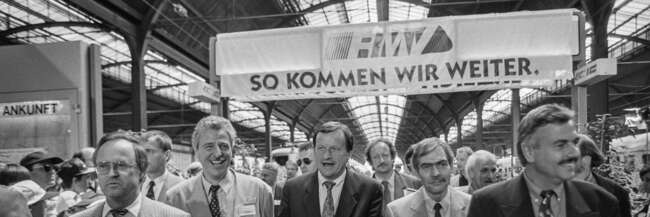 Schwarz-weiß-Foto im Frankfurter Hauptbahnhof mit Hans Eichel, Ministerpräsident des Landes Hessen (1991-1999), Lothar Klemm, Hessischer Verkehrsminister (1994-1999), Achim Exner, Oberbürgermeister der Stadt Wiesbaden (1985-1997), Jochen Riebel, Landrat des Main-Taunus-Kreises (1990-1999) und Volker Sparmann, RMV-Geschäftsführer (1995-2009).