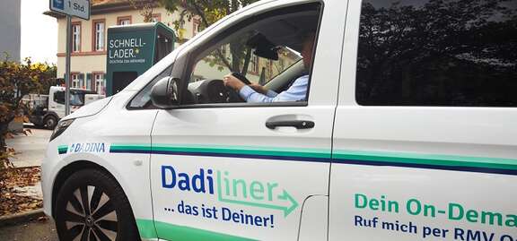 DadiLiner Babenhausen Ein weißes Auto steht auf einem Parkplatz. Schrift: DadiLiner...das ist deiner