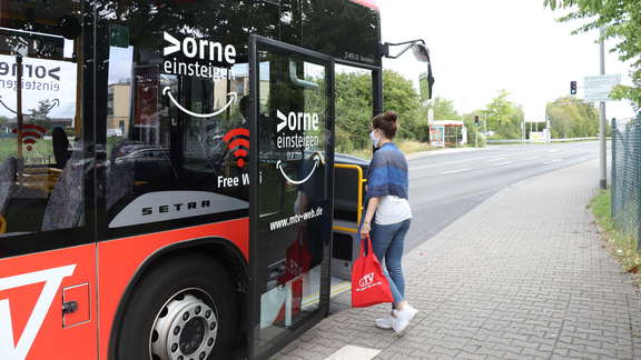 Fahrgast steigt durch die vordere Tür in den Bus ein.