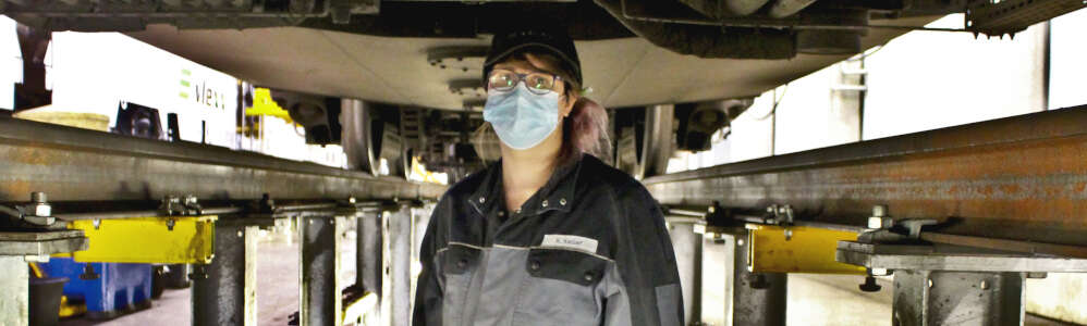 Frau in Arbeitsklamotten in der Arbeitsgruppe unter einem Zug