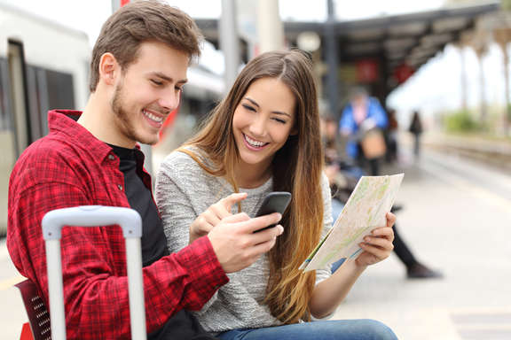 a young couple looking on a mobile phone sitting on the platform 