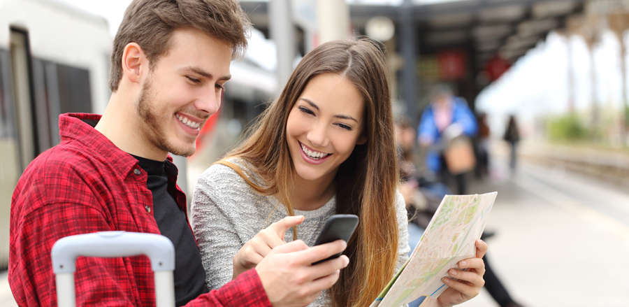 A young couple on the railway platform with a city map