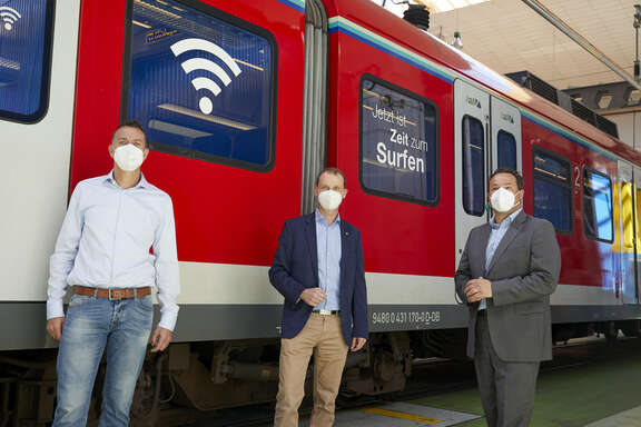 Guido Weißbrich, Netzchef Vodafone, Christian Roth, Leiter S-Bahn RheinMain, Dr. André Kavai, RMV-Geschäftsführer vor einer S-Bahn mit WLAN-Symbol