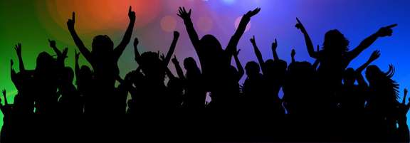 Crowd at a concert raising hands in the air. In the background coloured lights