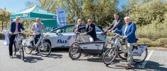 Politiker und RMV-Vorstand mit E-Fahrrädern und Elektroautos vom Sharing-Anbieter flux.