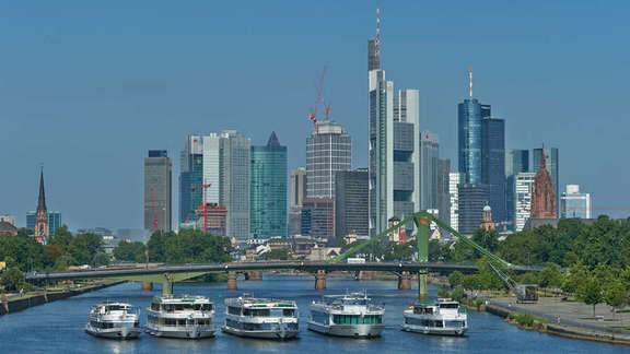 Vergrößerte Ansicht: Fünf Schiffe nebeneinander vor einer Brücke, dahinter die Skyline Frankfurts