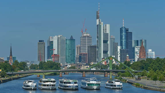 Five ships side by side in front of a bridge, behind them the skyline of Frankfurt