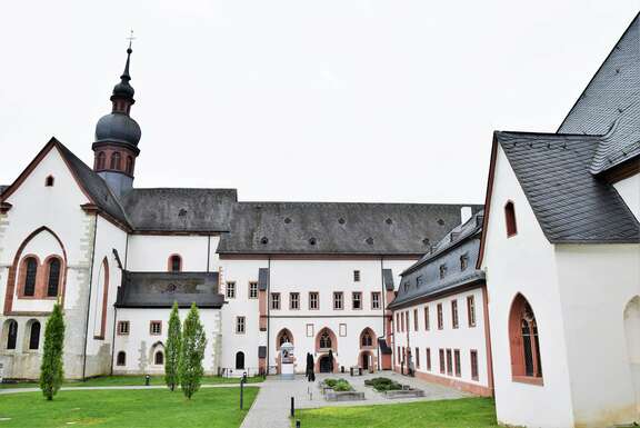 Weiß gestrichene Gebäude mit Turmspitze, davor Grünfläche